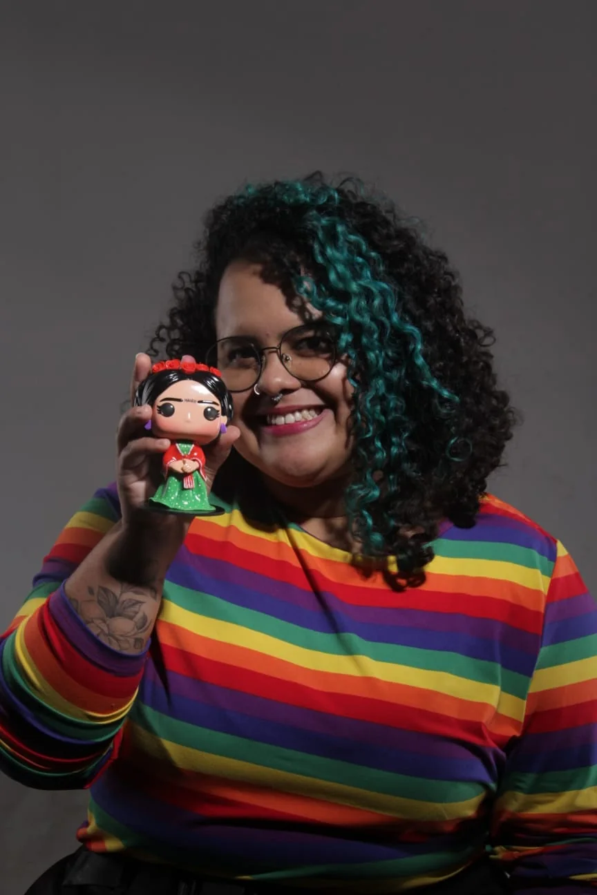 Lucy segurando um Pop personalizado da Frida Kahlo, com vestido verde e coroa de flores vermelhas, feito à mão no ateliê