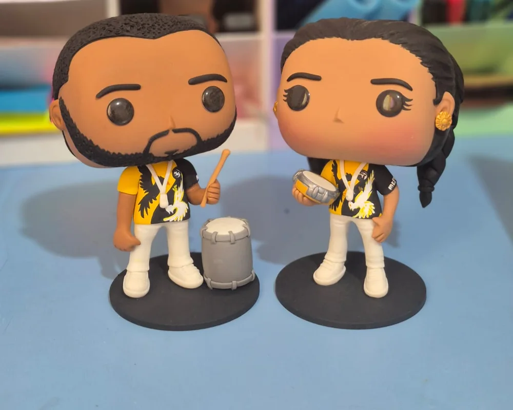 Pop de casal de ritmistas: as duas peças com camisa de escola de samba, uma com surdo e outra com tamborim