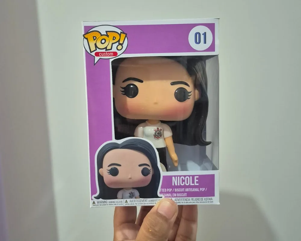 Pop personalizado da Nicole, de cabelo preto liso e camiseta do Corinthians, feito à mão em biscuit, dentro da caixa impressa do ateliê
